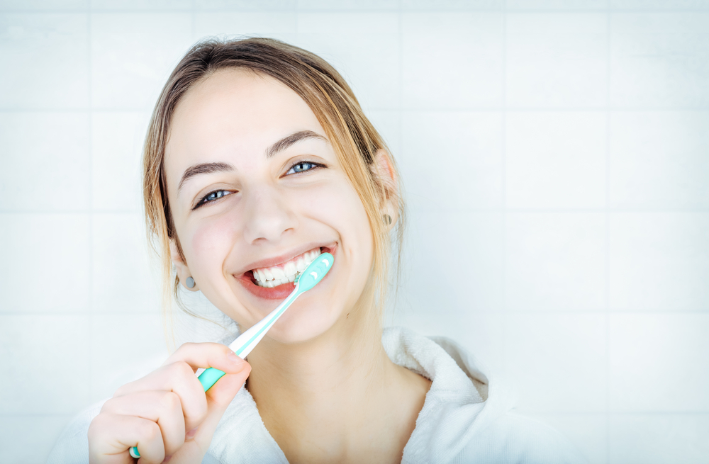 happy young woman brushes teeth